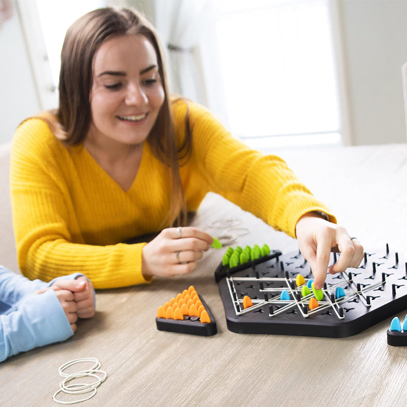 Main d'enfant plaçant un pion LinkLogic sur le plateau, illustrant la résolution de puzzle coopérative et la stratégie.