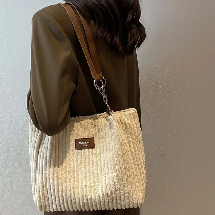 Sac femme en velours côtelé, pratique avec son grand espace, ajoute une touche chic à la tenue.