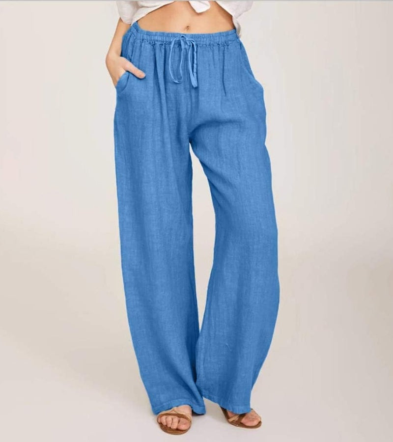 Femme marchant, portant un pantalon large taille haute en lin, pour un look estival confortable.