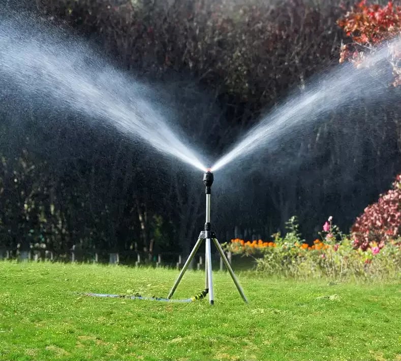 Équipement de jardin: arroseur rotatif automatique sur trépied pour un arrosage complet et uniforme.