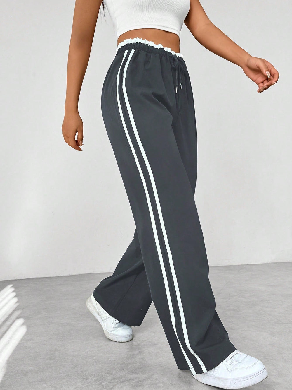 Pantalon femme taille haute, coupe ample, style sportif moderne. Idéal pour les loisirs et un look décontracté chic.