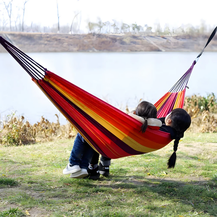 Hamac de jardin rayé coloré en tissu, parfait pour la détente estivale confortable en extérieur.