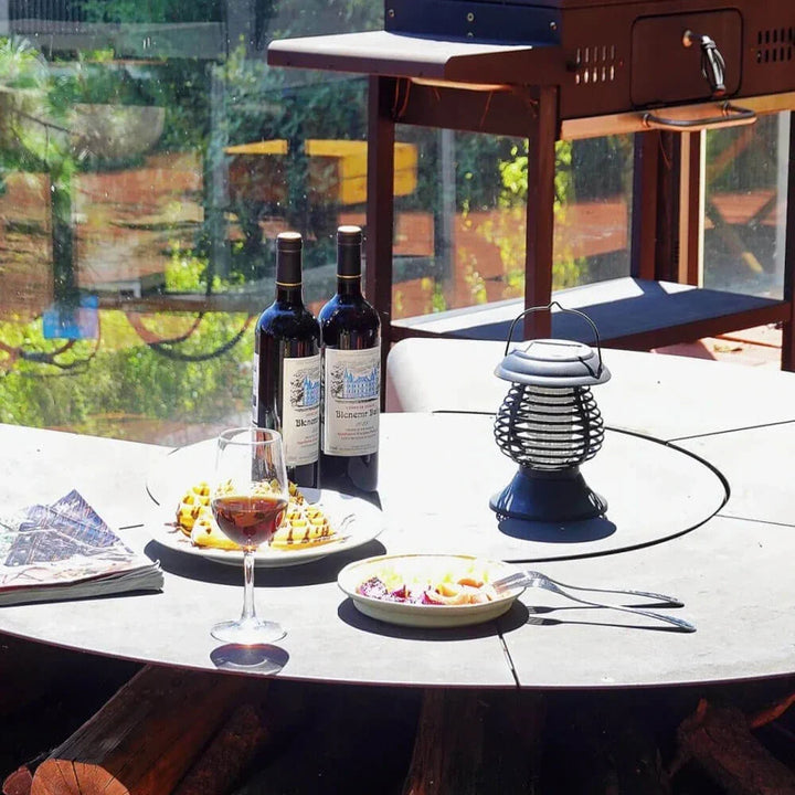 Lampe anti-moustiques solaire LED sur table de terrasse, créant une ambiance lumineuse et protégeant des insectes.