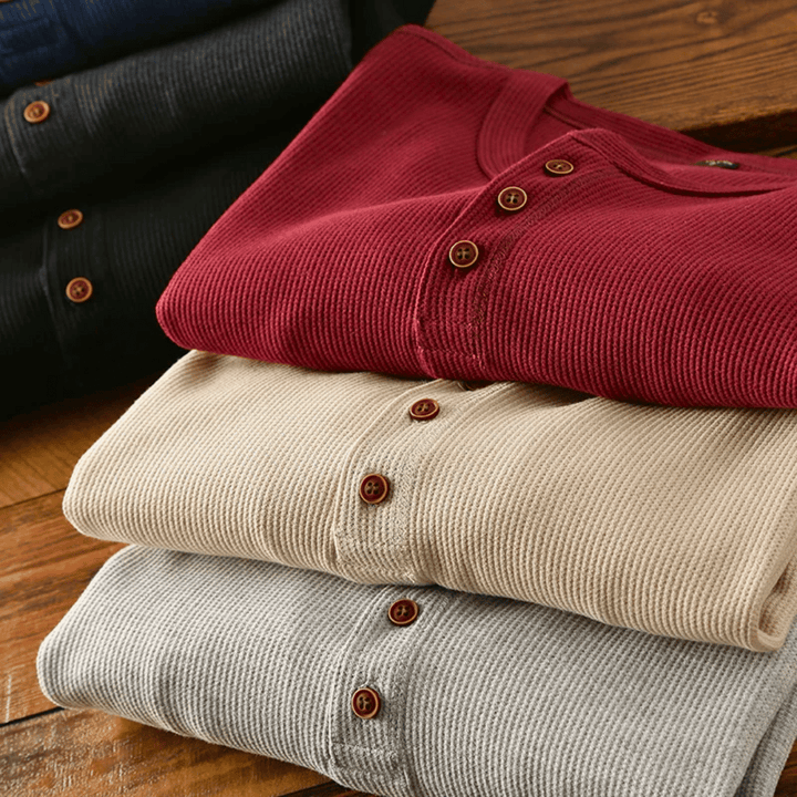 Pull Henley homme plié, mettant en valeur son tissu de qualité et son design chic. Mode masculine essentielle.