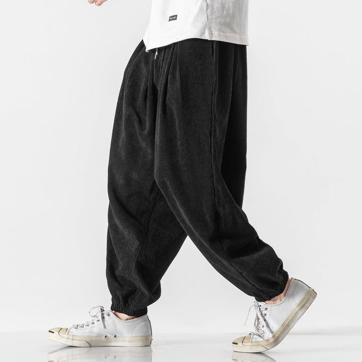 Homme portant un pantalon large gris, coupe décontractée moderne, offrant un confort absolu.