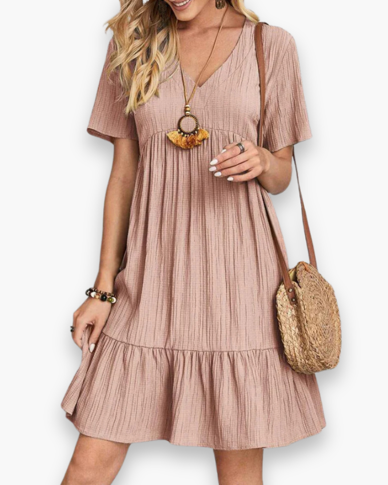 Femme portant une robe d'été mini bohème, confortable et chic pour une tenue de plage décontractée.
