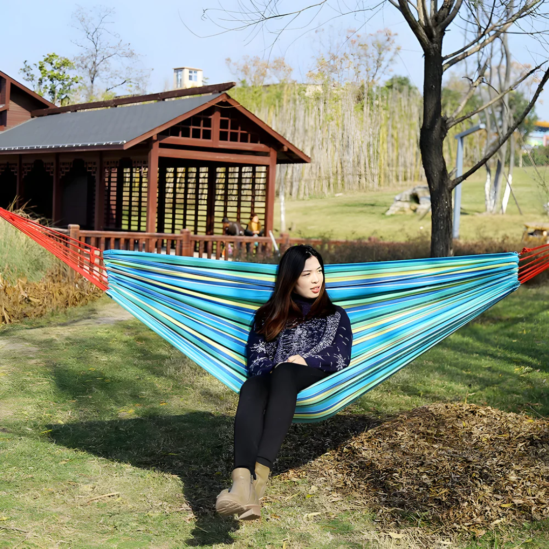 Hamac rayé portable pour jardin, balcon ou camping, offrant confort et relaxation en été.