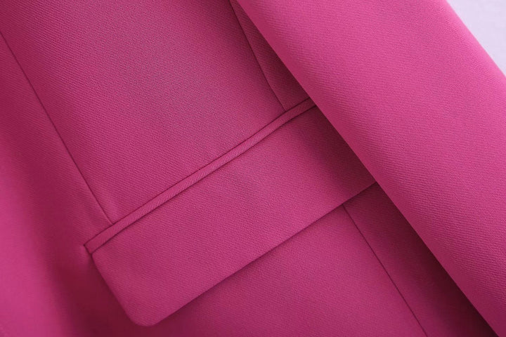 Femme en ensemble rose poudré, blazer et pantalon élégants, style professionnel et tendance.