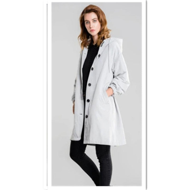 Femme portant un manteau de pluie chic avec capuche, look élégant et protection contre la pluie.