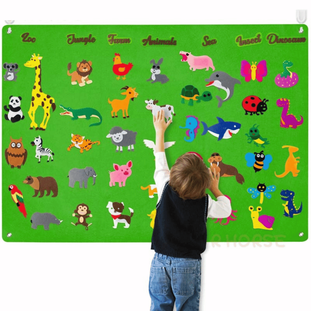 Enfant joue avec le tableau en feutre éducatif, créant des scènes d'animaux, développant sa créativité.