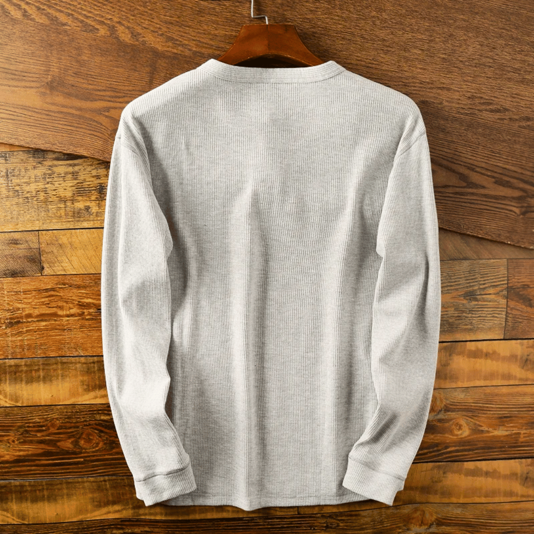 Détail du col Henley boutonné et du tissu doux de ce pull homme. Confort et style masculin assurés.