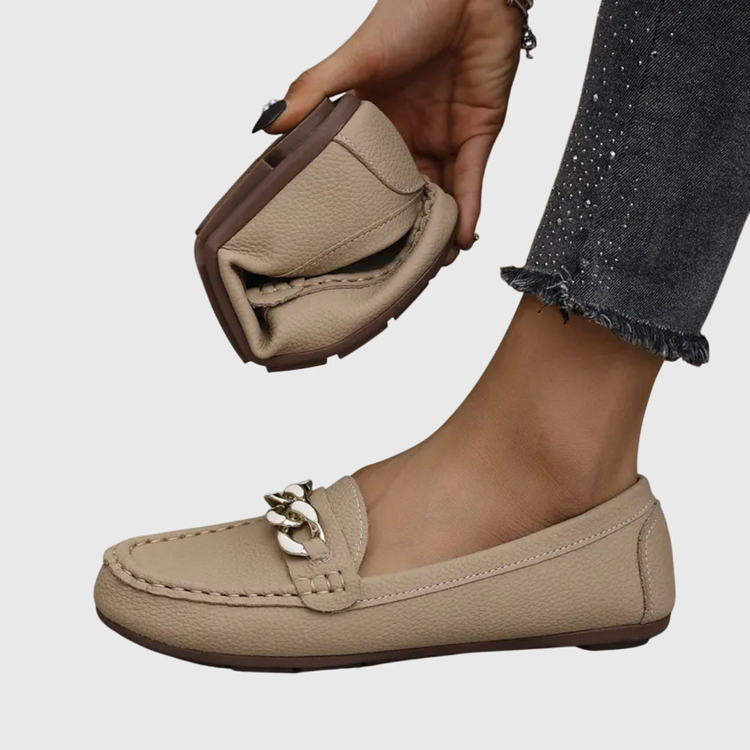 Mocassins pour femme en cuir lisse, bout rond, et chaîne décorative. Chaussures confortables et intemporelles.