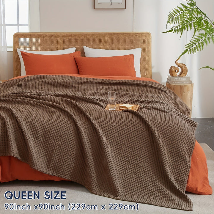 Plaid Cloudweave beige, douce et légère, idéale pour créer une atmosphère cocooning et invitante.