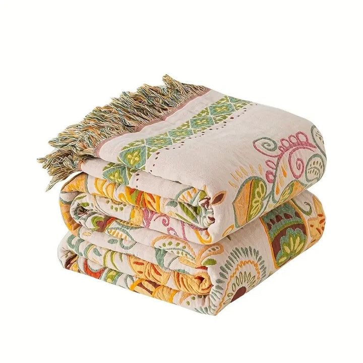 Couverture réversible en gaze de coton motif feuilles d'automne, avec pompons décoratifs. Idéale pour lit ou canapé.
