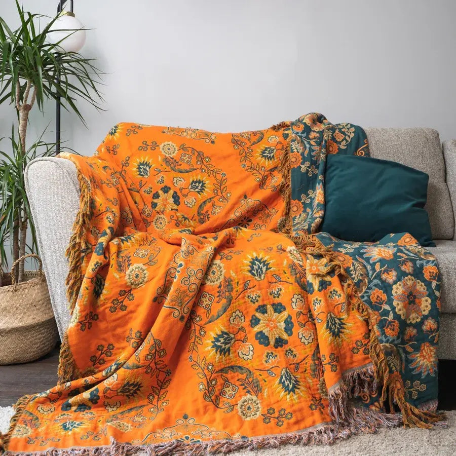 Couverture florale orange et bleu sarcelle pour canapé, réversible, apporte une touche de légèreté à la maison.