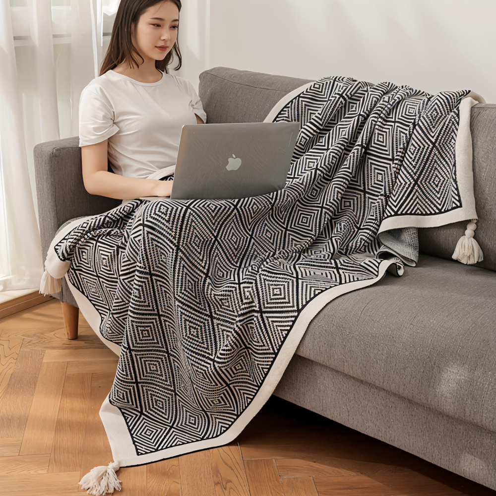 Plaid doux noir et blanc, motif géométrique moderne, parfait pour lit ou canapé, style scandinave.