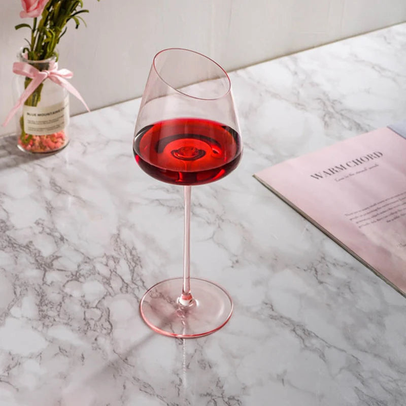 Gros plan sur un verre à vin rose en cristal soufflé bouche, révélant sa beauté artisanale et couleur unique.