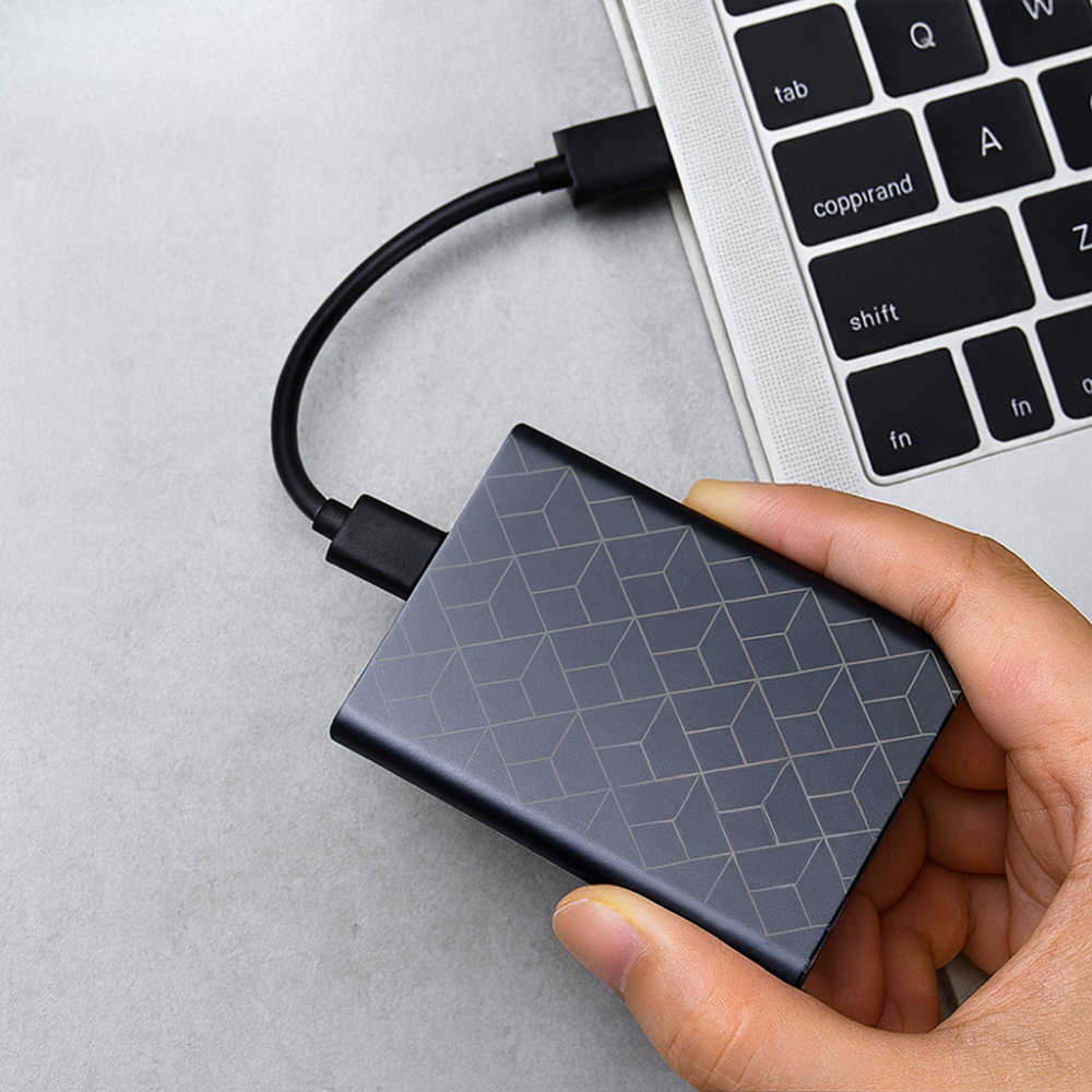 SSD externe portable connecté à un ordinateur via USB-C, transfert ultra-rapide de fichiers multimédias.