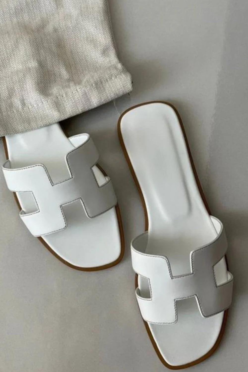 Sandales plates femme confortables et minimalistes, idéales pour l'été. Mules élégantes à bride H.