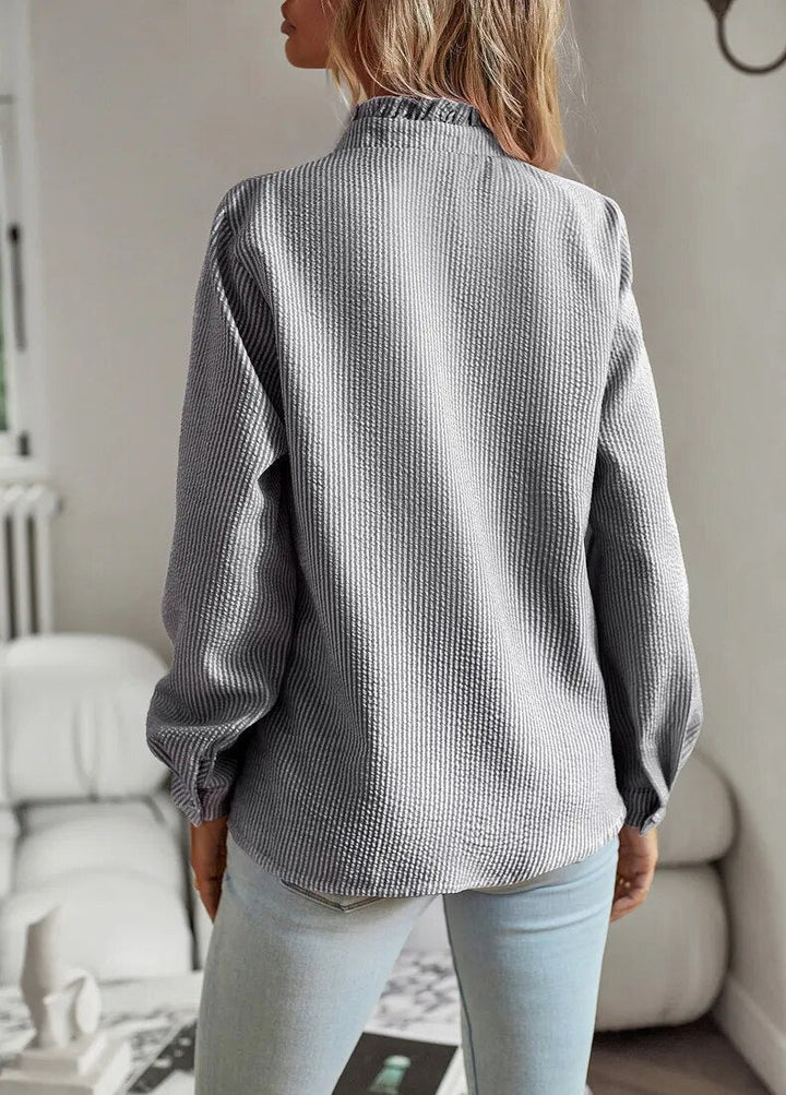 Chemisier femme ajusté, col montant, manches longues. Élégant et formel, idéal pour une tenue de bureau soignée.