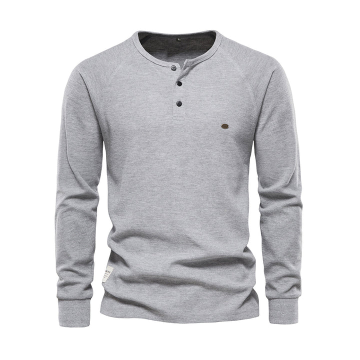 Homme souriant portant un t-shirt Henley à manches longues. Col boutonné, style décontracté et moderne pour l'homme.