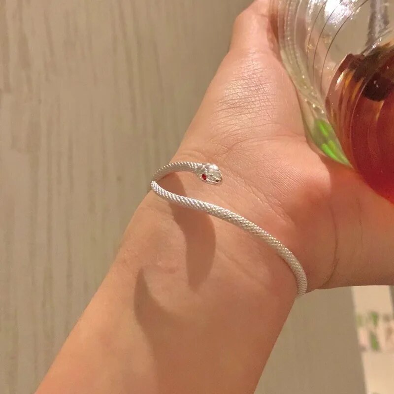 Gros plan d'un bracelet serpent ajustable en argent, détails fins et brillance naturelle du métal.