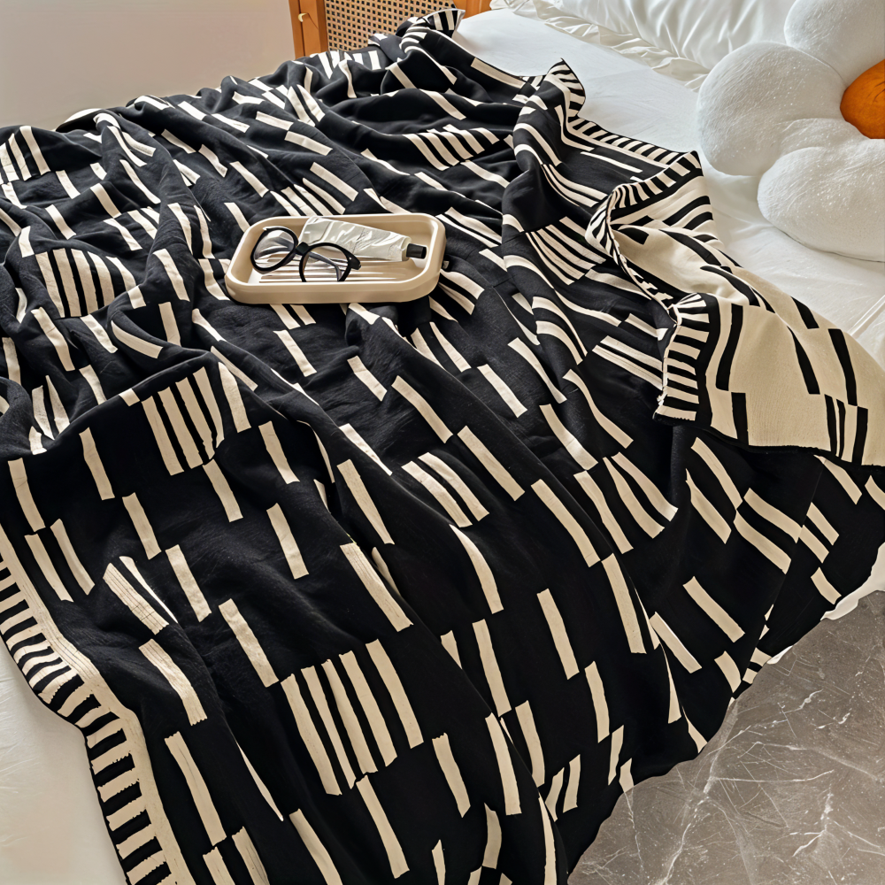 Plaid décoratif tricoté noir et beige, élégant pour salon ou chambre, apporte chaleur et style.
