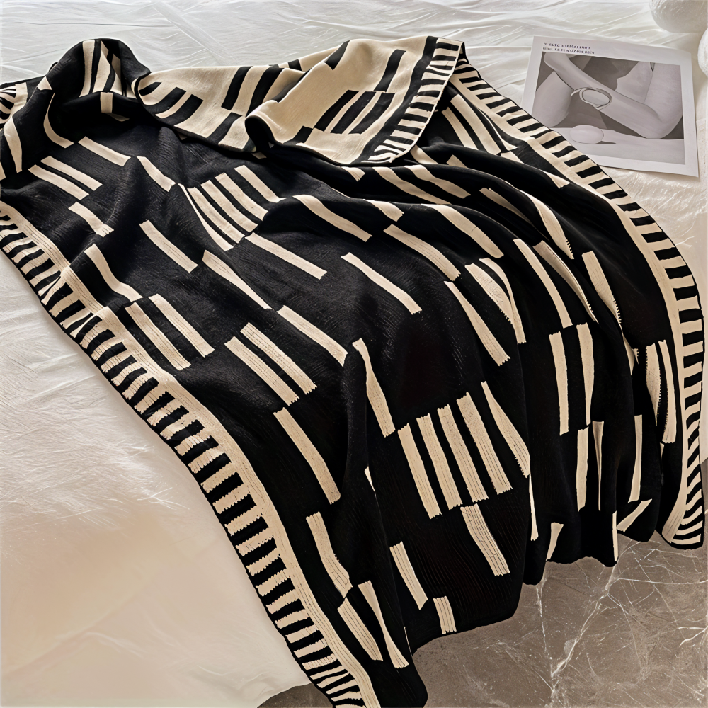 Couverture plaid tricotée noir et beige en acrylique, idéale pour décorer et réchauffer canapé ou lit.