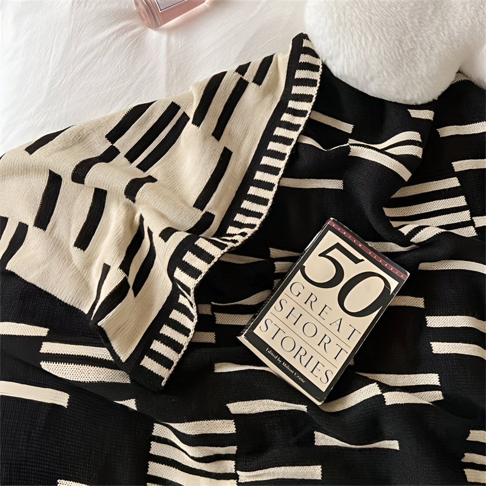Plaid tricoté noir et beige, doux et léger, parfait pour des moments cocooning sur le lit ou canapé.