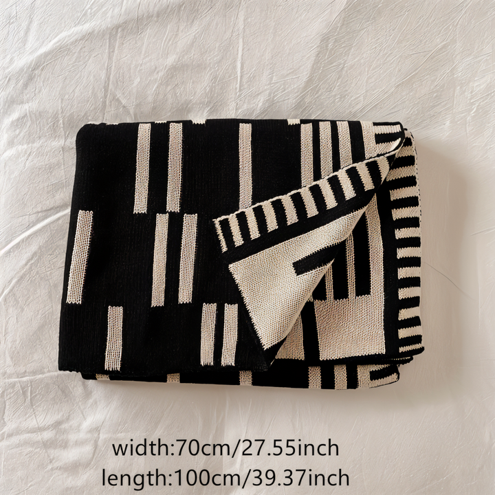 Plaid tricoté noir et beige, léger et confortable, idéal pour décorer salon ou chambre avec style.