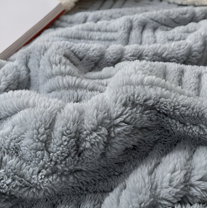 Gros plan sur la texture douce du plaid géométrique réversible, polyester moelleux et chaud.