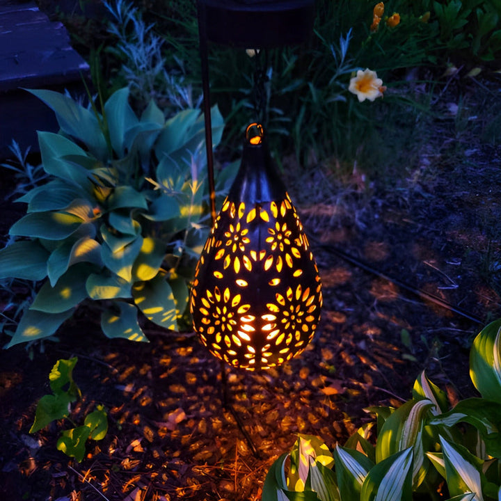 Gros plan sur une lanterne solaire décorative en métal ajouré, montrant la lumière LED douce et chaude.