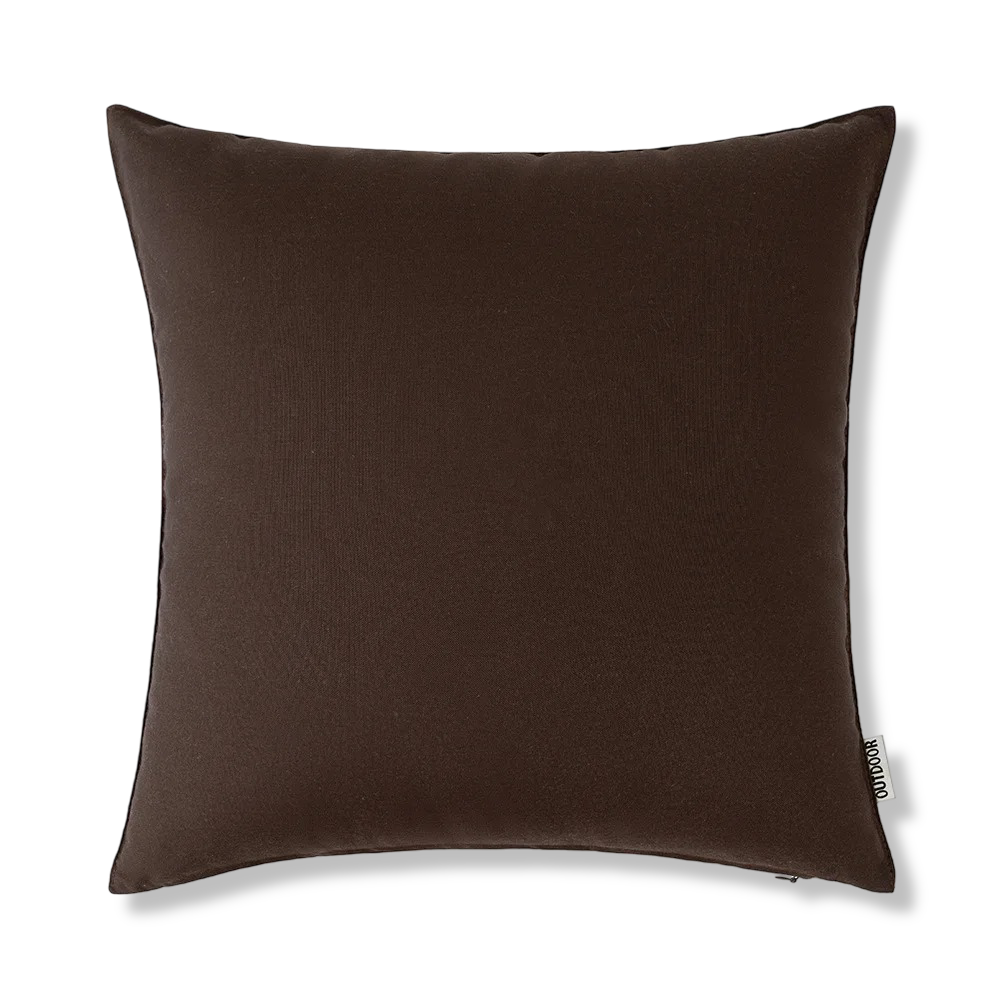 Housse coussin 45x45 cm, effet lin, déperlante, entourée de verdure dans un jardin luxuriant.
