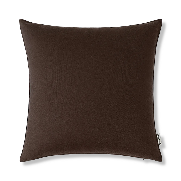 Housse coussin 45x45 cm, effet lin, déperlante, entourée de verdure dans un jardin luxuriant.