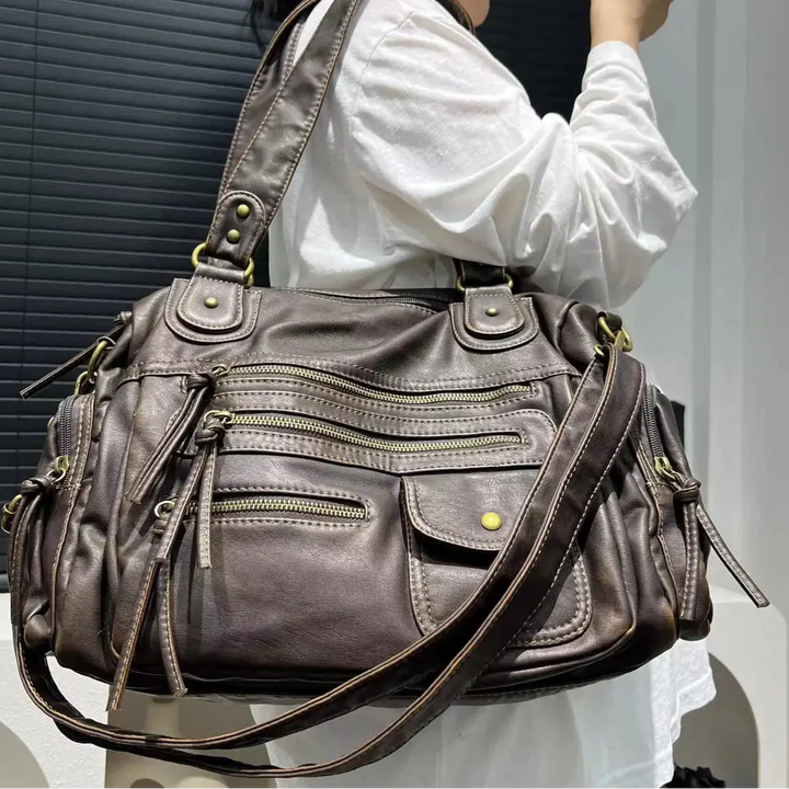 Détail du sac à main vintage multi-poches en simili cuir noir, avec fermetures éclair et bandoulière réglable.