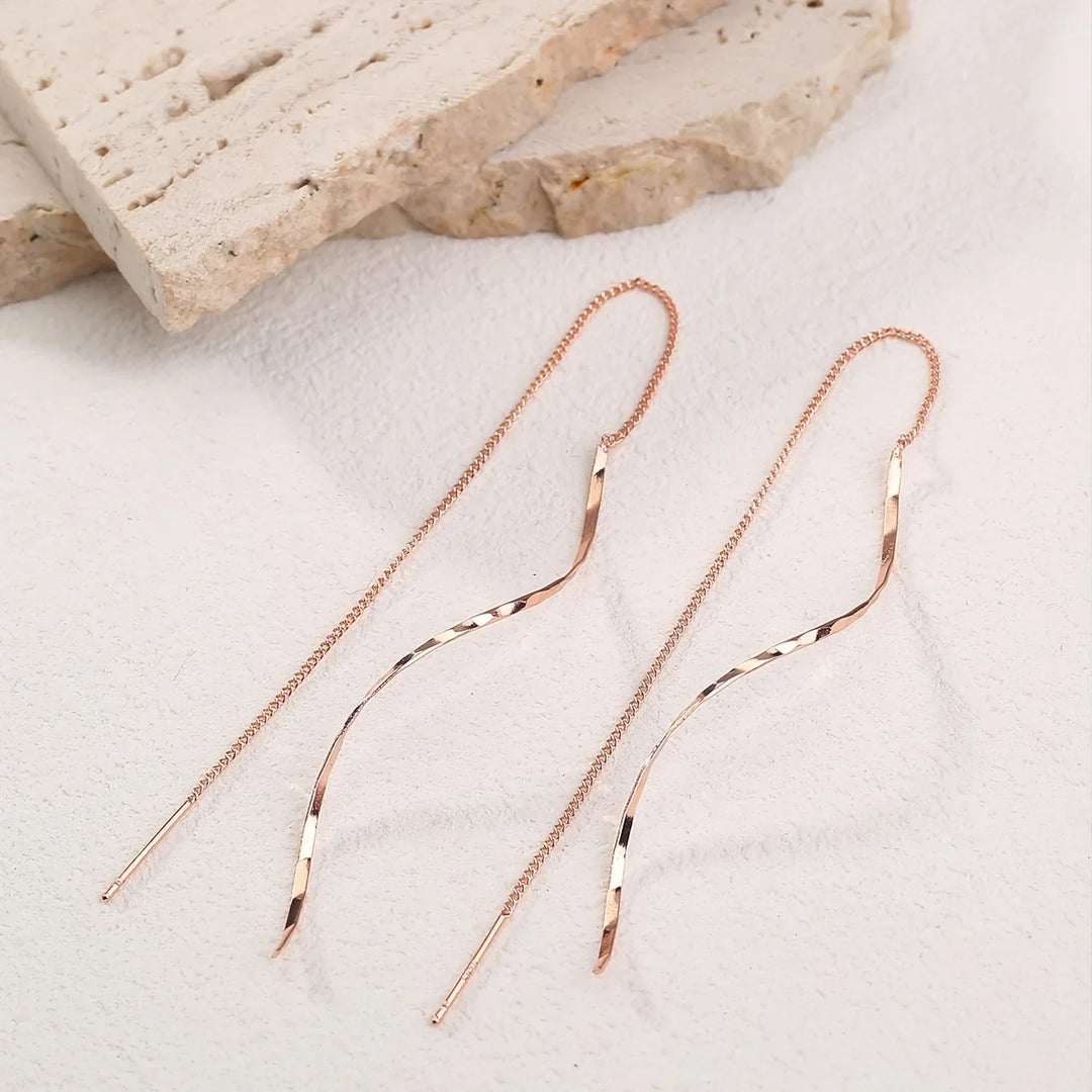 Accessoire mode: boucles d'oreilles longues vagues en or, pour un look chic et tendance.