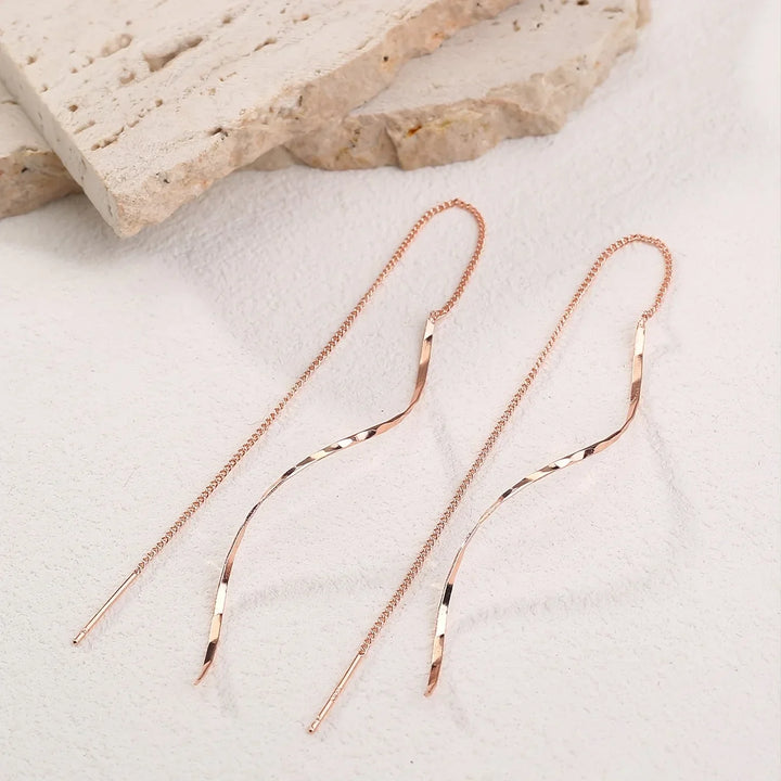 Accessoire mode: boucles d'oreilles longues vagues en or, pour un look chic et tendance.