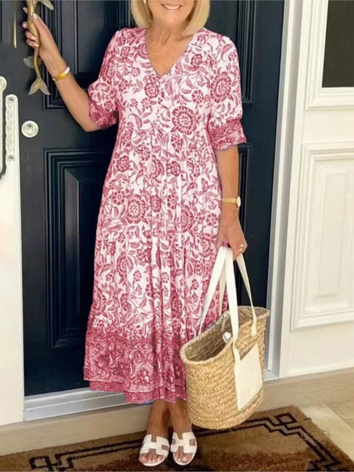 Femme portant une robe longue florale estivale décontractée. Col en V, coupe fluide, parfaite pour le printemps/été.