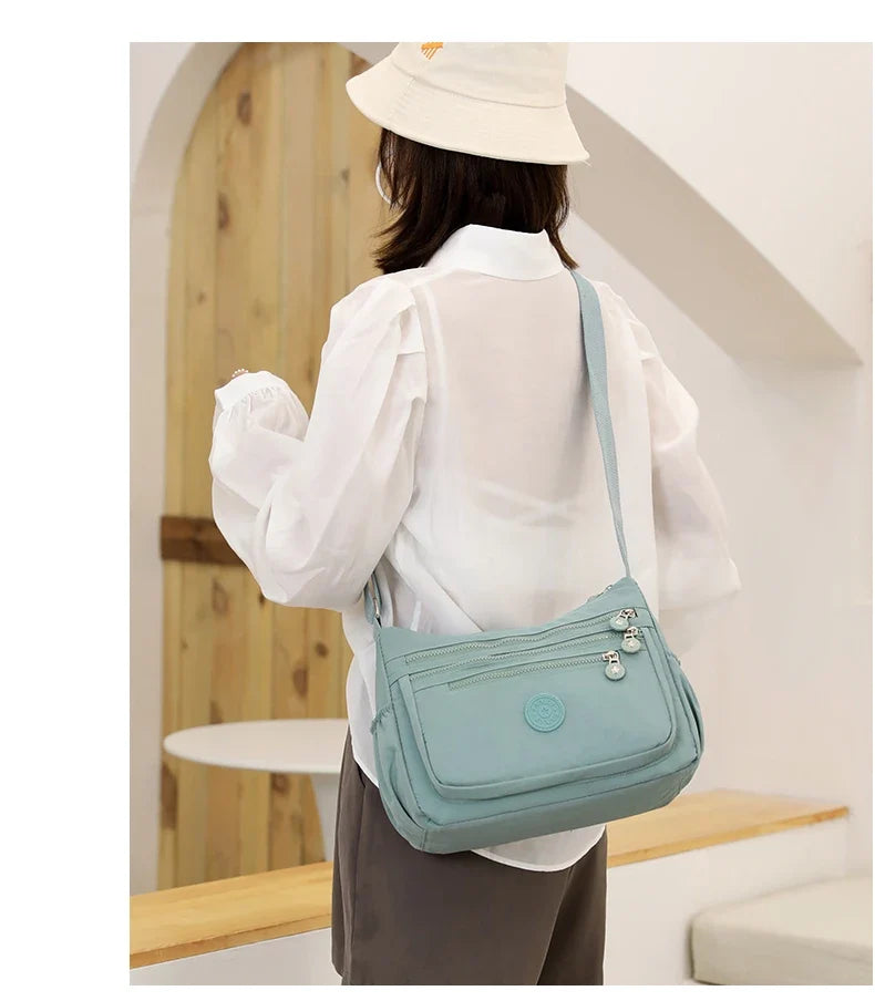 Sac bandoulière voyage femme, en nylon déperlant, alliant sécurité, organisation et style.