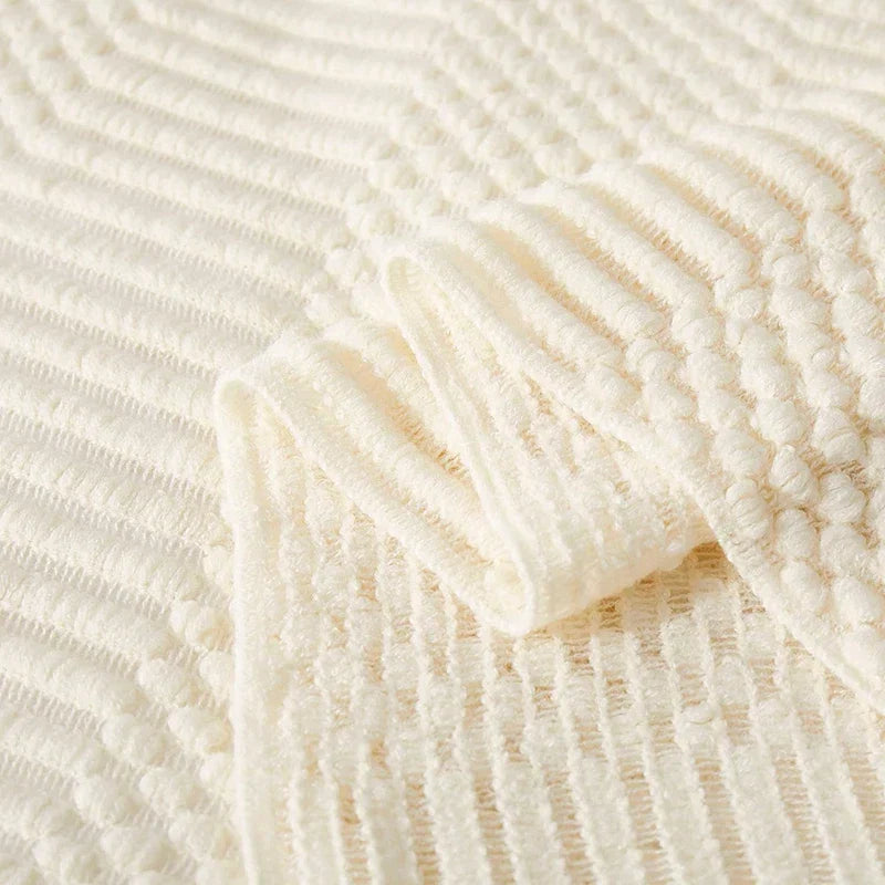 Détail texturé d'une couverture tricot bohème beige, idéale pour une déco cocooning et chaleureuse.