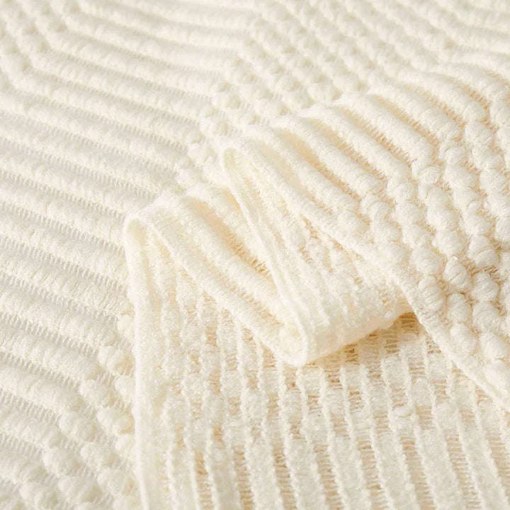 Détail texturé d'une couverture tricot bohème beige, idéale pour une déco cocooning et chaleureuse.