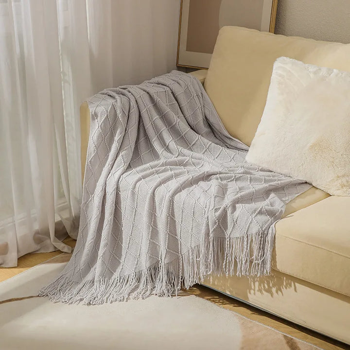 Gros plan sur la texture des mailles d'une couverture tricot bohème, soulignant sa qualité et sa douceur.