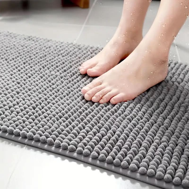 Tapis de bain en chenille grise, absorbant et antidérapant, apporte douceur et sécurité à votre salle de bain.