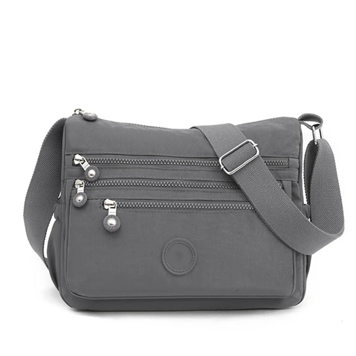 Sac bandoulière de voyage en nylon résistant et déperlant, avec plusieurs compartiments pratiques.