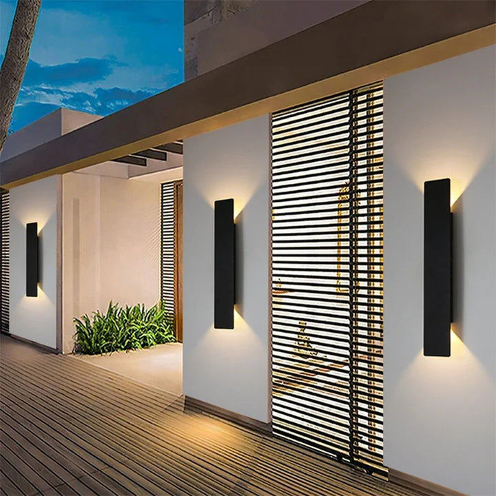Luminaire applique LED extérieure linéaire moderne, projette lumière haut/bas décorative sur façade.
