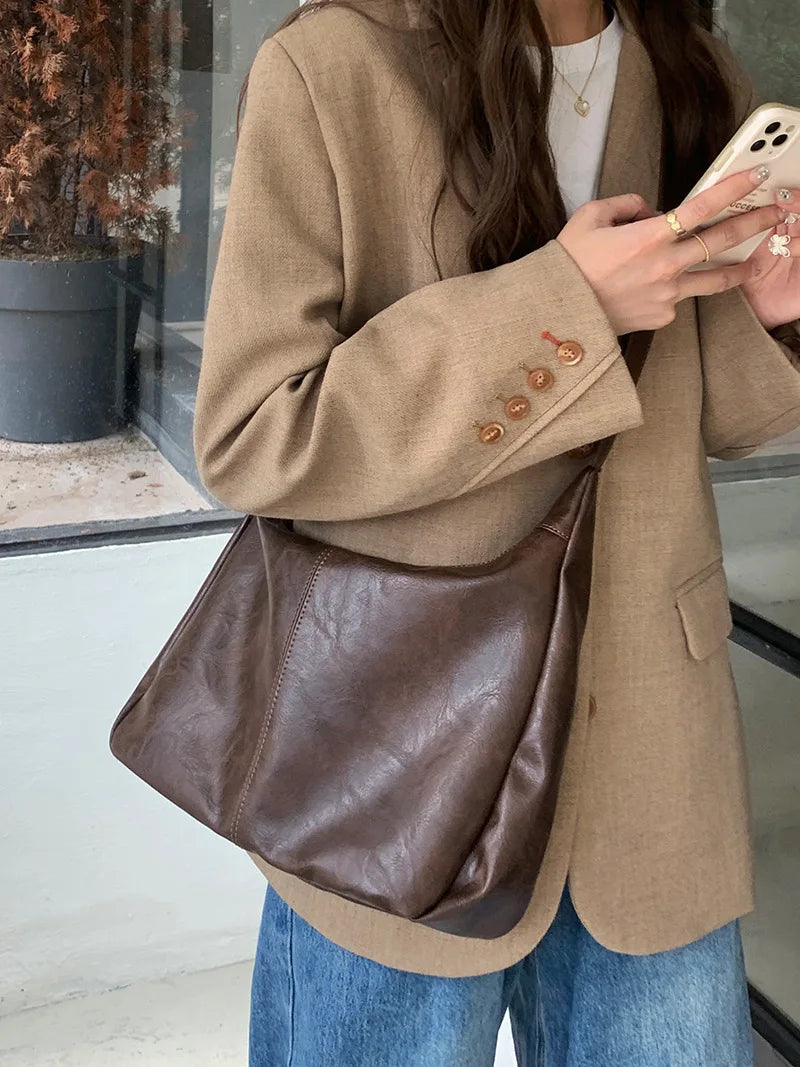Sac à main bandoulière femme élégant en similicuir noir, accessoire tendance pour un look quotidien chic.
