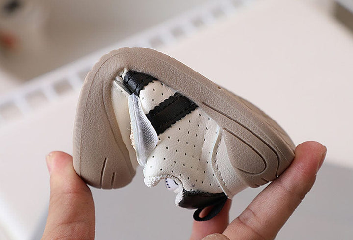 Chaussures de marche bébé noires, souples et ergonomiques, favorisant le mouvement naturel des pieds de l'enfant.