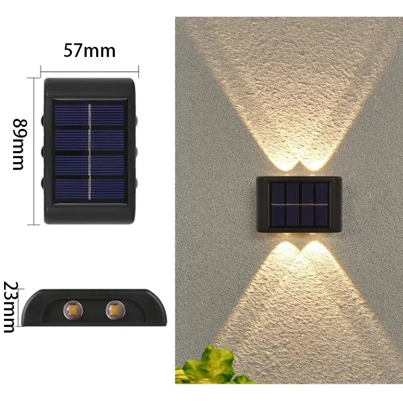 Applique murale solaire LED bidirectionnelle éclairant la façade d'une maison et le chemin du jardin la nuit.