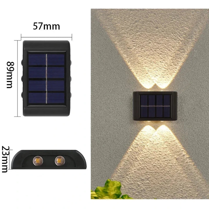 Applique murale solaire LED bidirectionnelle éclairant la façade d'une maison et le chemin du jardin la nuit.