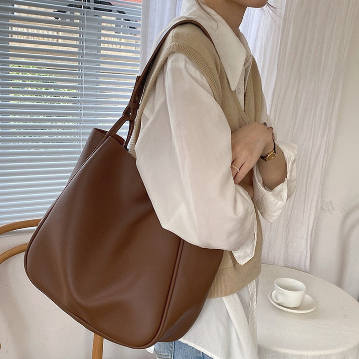 Gros plan sur la texture douce du sac à main cabas marron en cuir vegan polyuréthane, finitions élégantes.